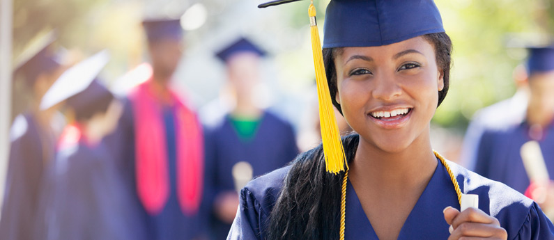 Smiling graduate wearing graduation cap and gown after receiving financial aid.